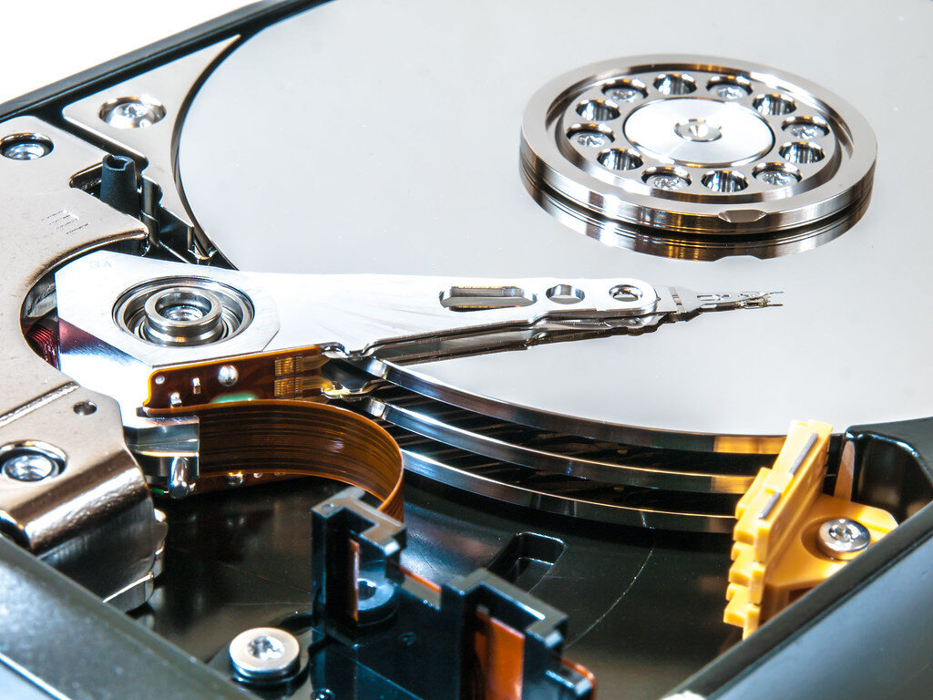 Geöffnete Festplatte in Nahaufnahme mit spiegelnder Magnetscheibe und Schreib-Lese-Arm