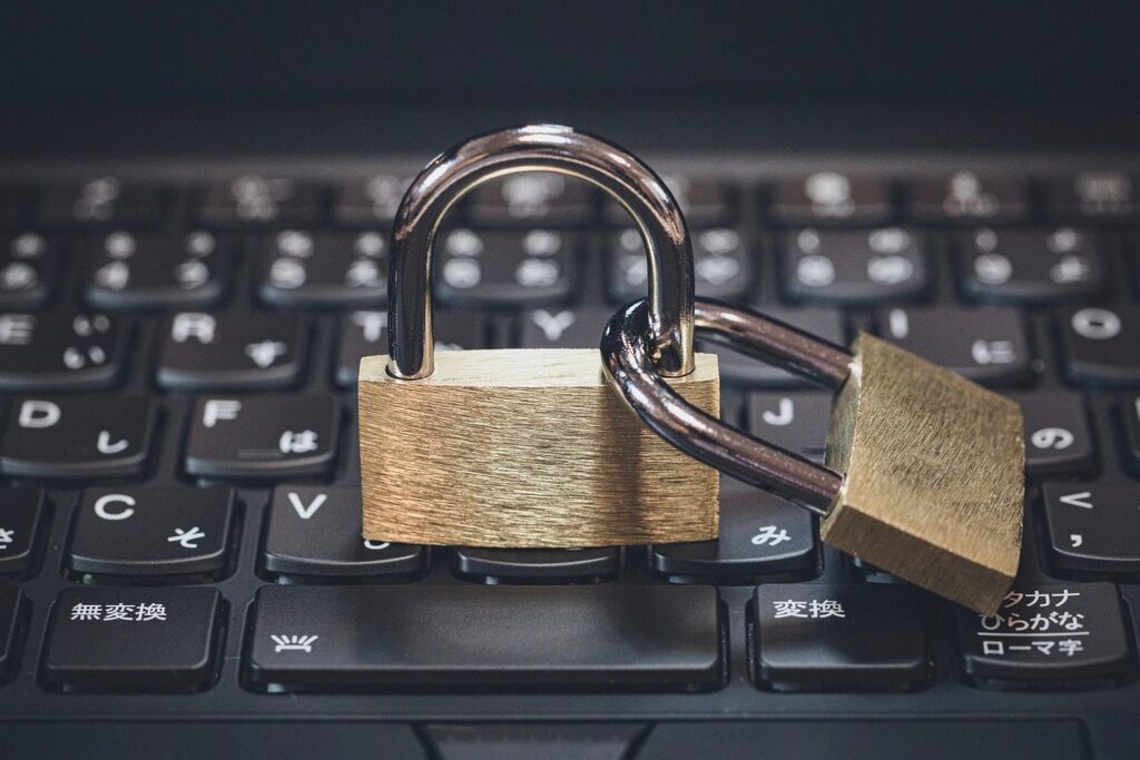 Geschlossenes Messing-Vorhängeschloss liegt auf der Tastatur eines schwarzen Laptops